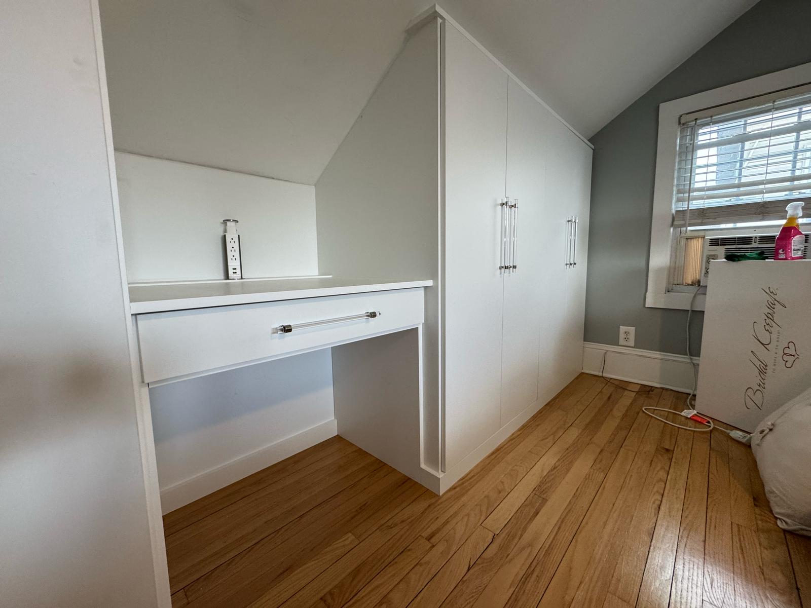 Bedroom built-in desk and storage with white cabinets and integrated workspace design