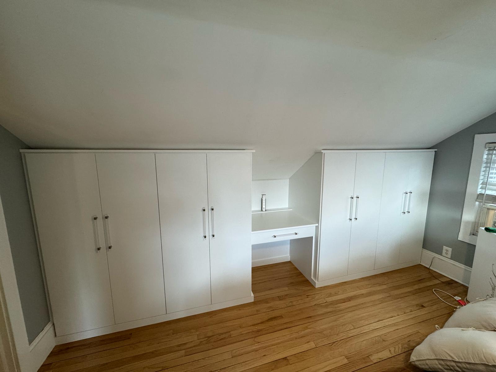 Bedroom built-in storage wall with floor-to-ceiling cabinets and integrated desk workspace