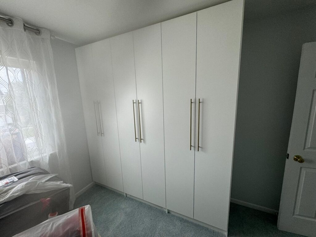 Bedroom reach-in closet with white floor-to-ceiling doors and modern hardware handles