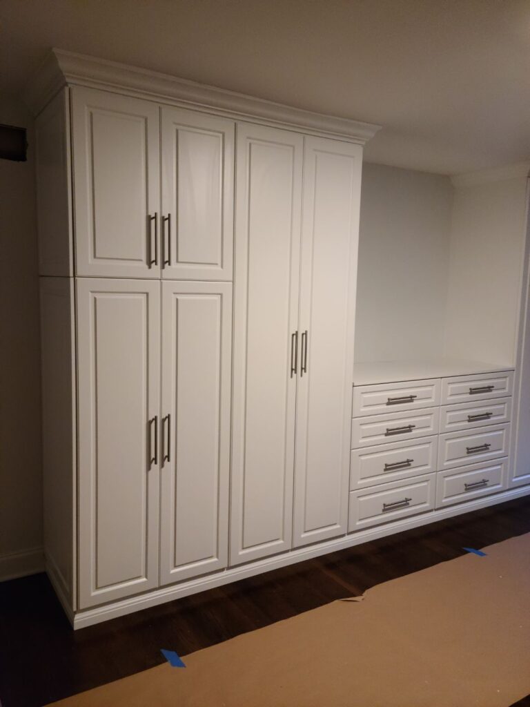 Bedroom wall storage system with central TV niche, multiple drawers, and built-in cabinets