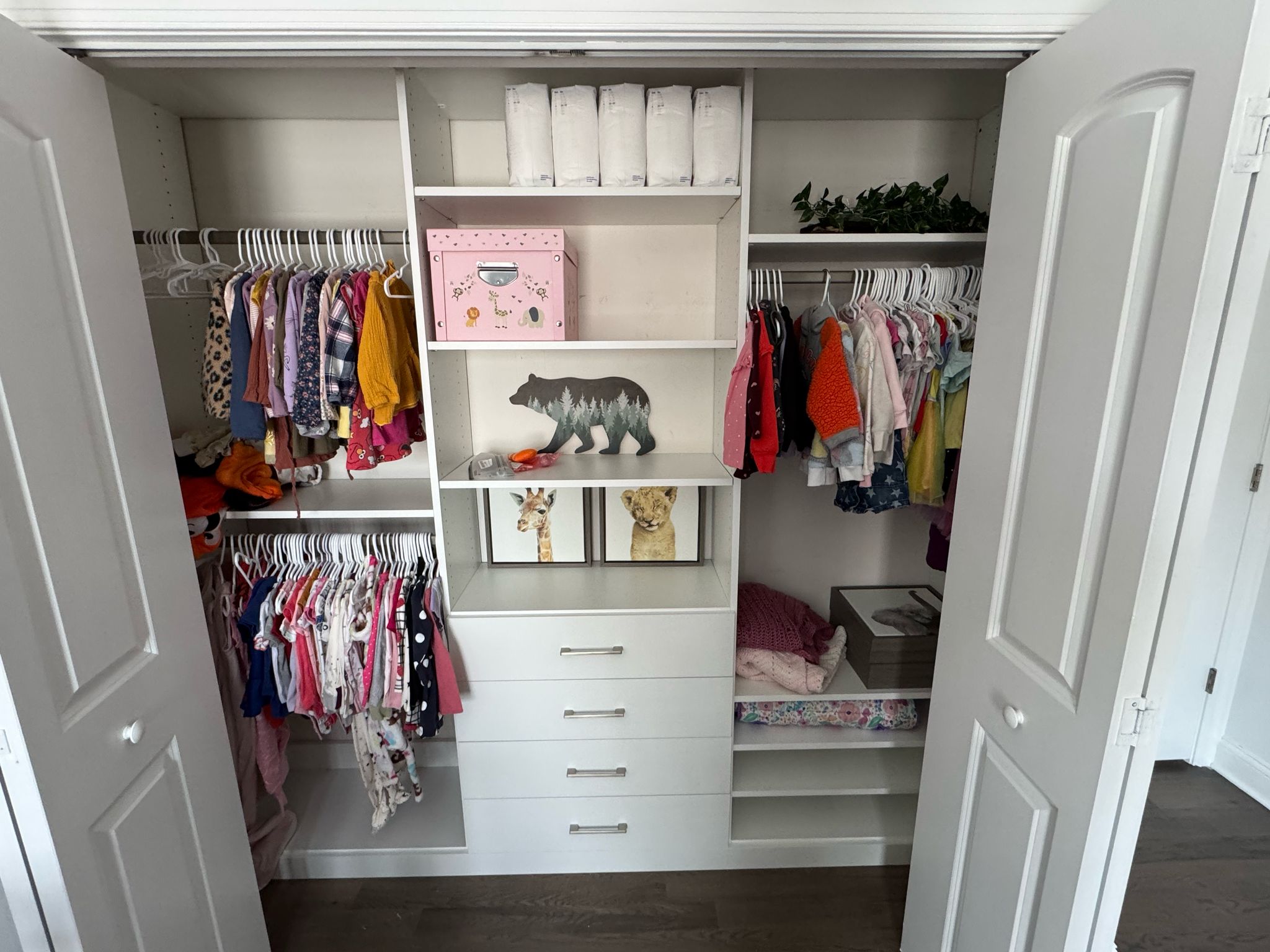 Children's reach-in closet with organized kids clothes, central tower, and colorful storage accessories