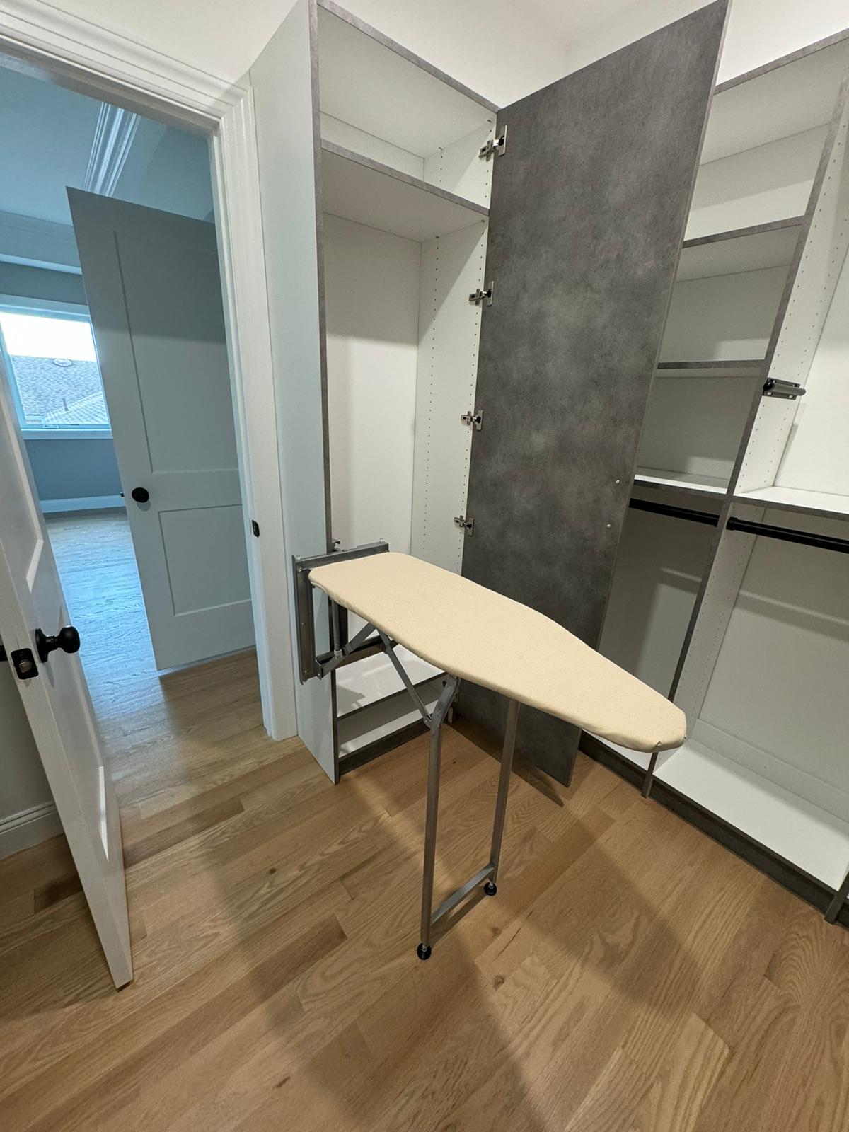 Closet featuring pull-out ironing board with white storage systems and specialized utility features