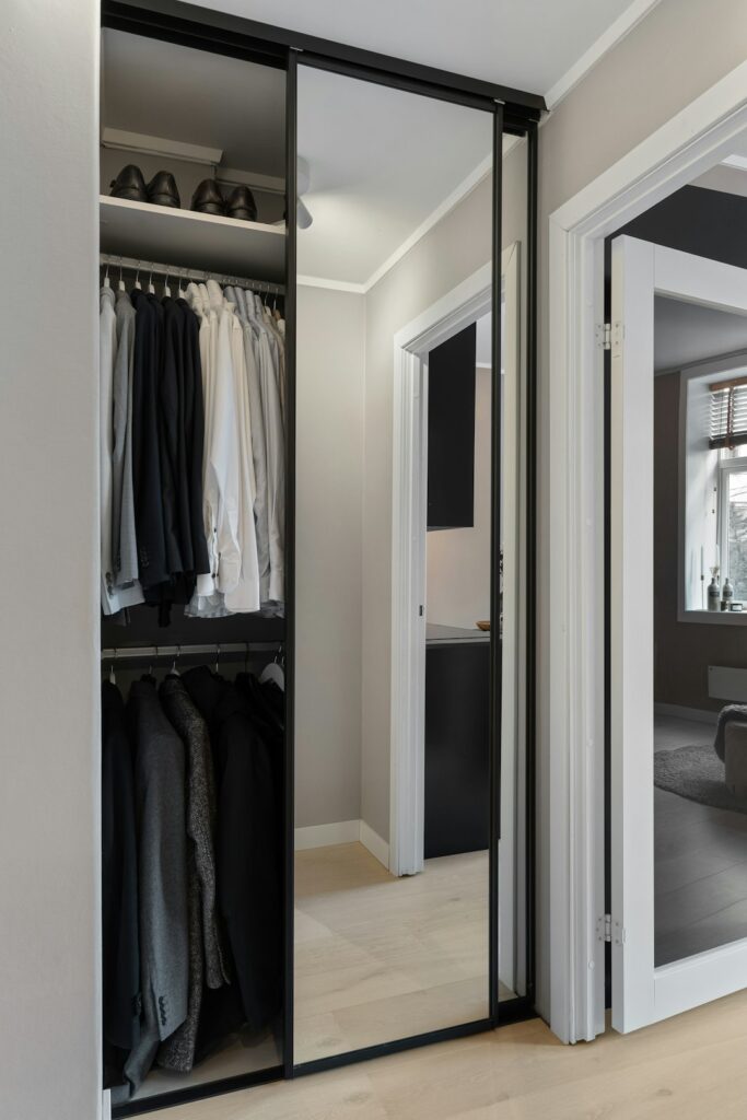 Compact reach-in closet with black-framed sliding doors and efficient white storage organization