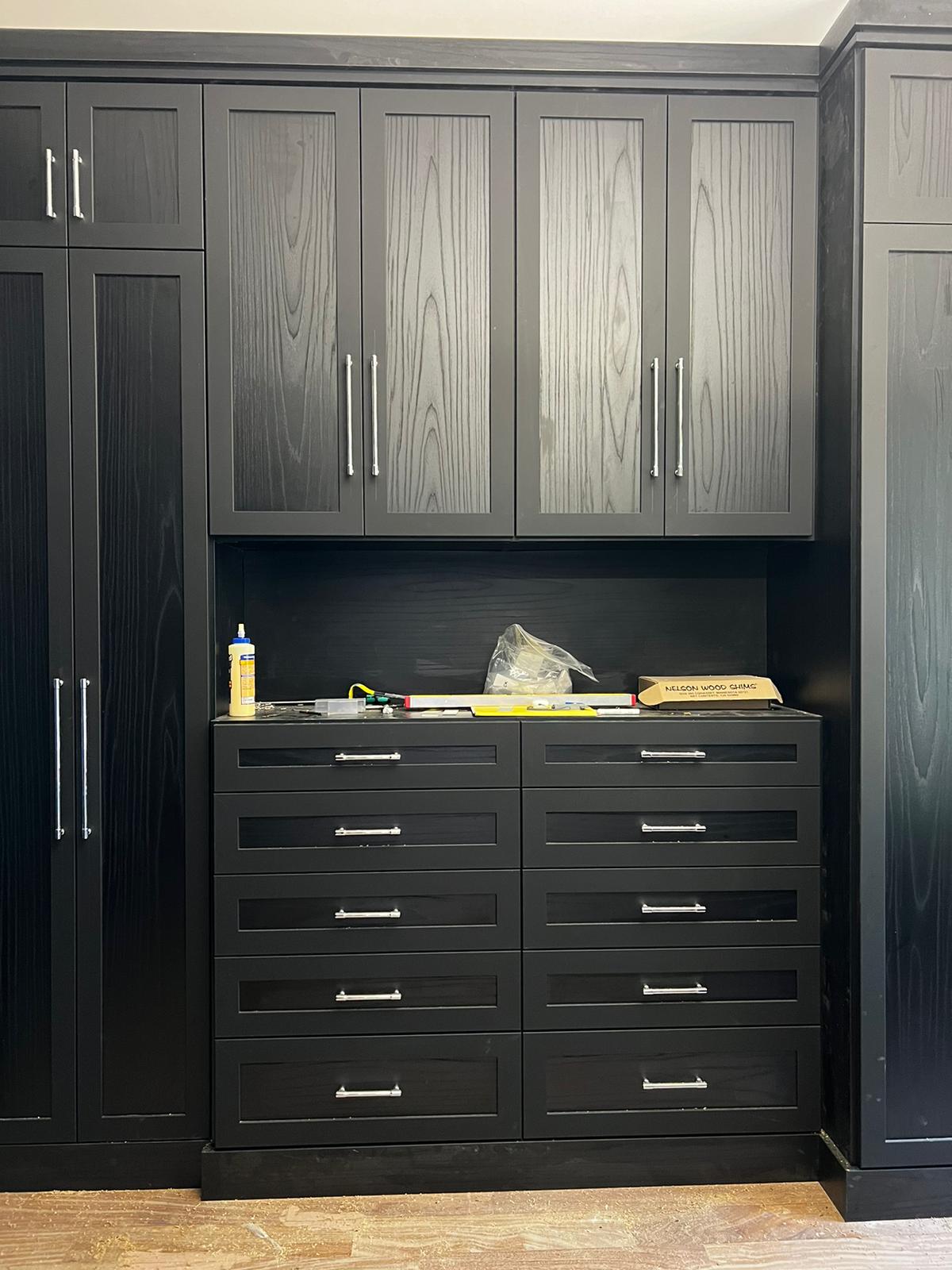 Custom garage storage and workshop area with dark wood grain cabinets and extensive organization