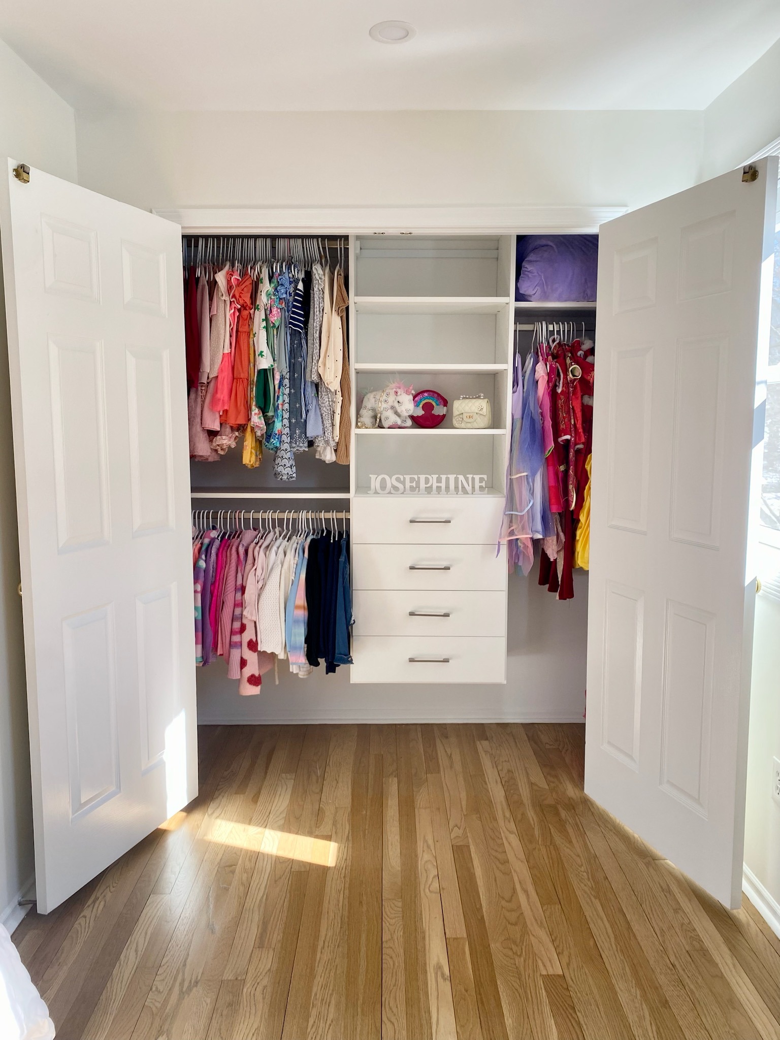 Girls reach-in closet with organized dresses, accessories, and colorful storage solutions