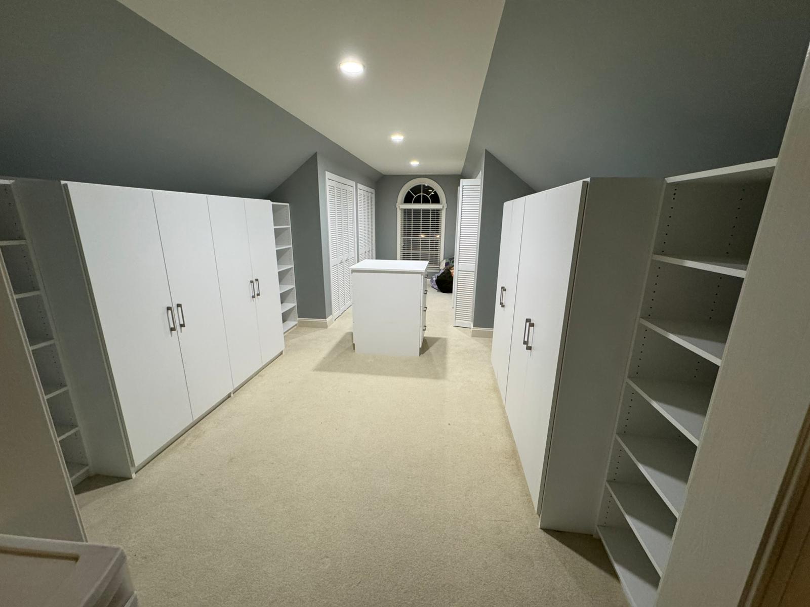 Large empty walk-in closet with extensive white cabinets and floor-to-ceiling storage