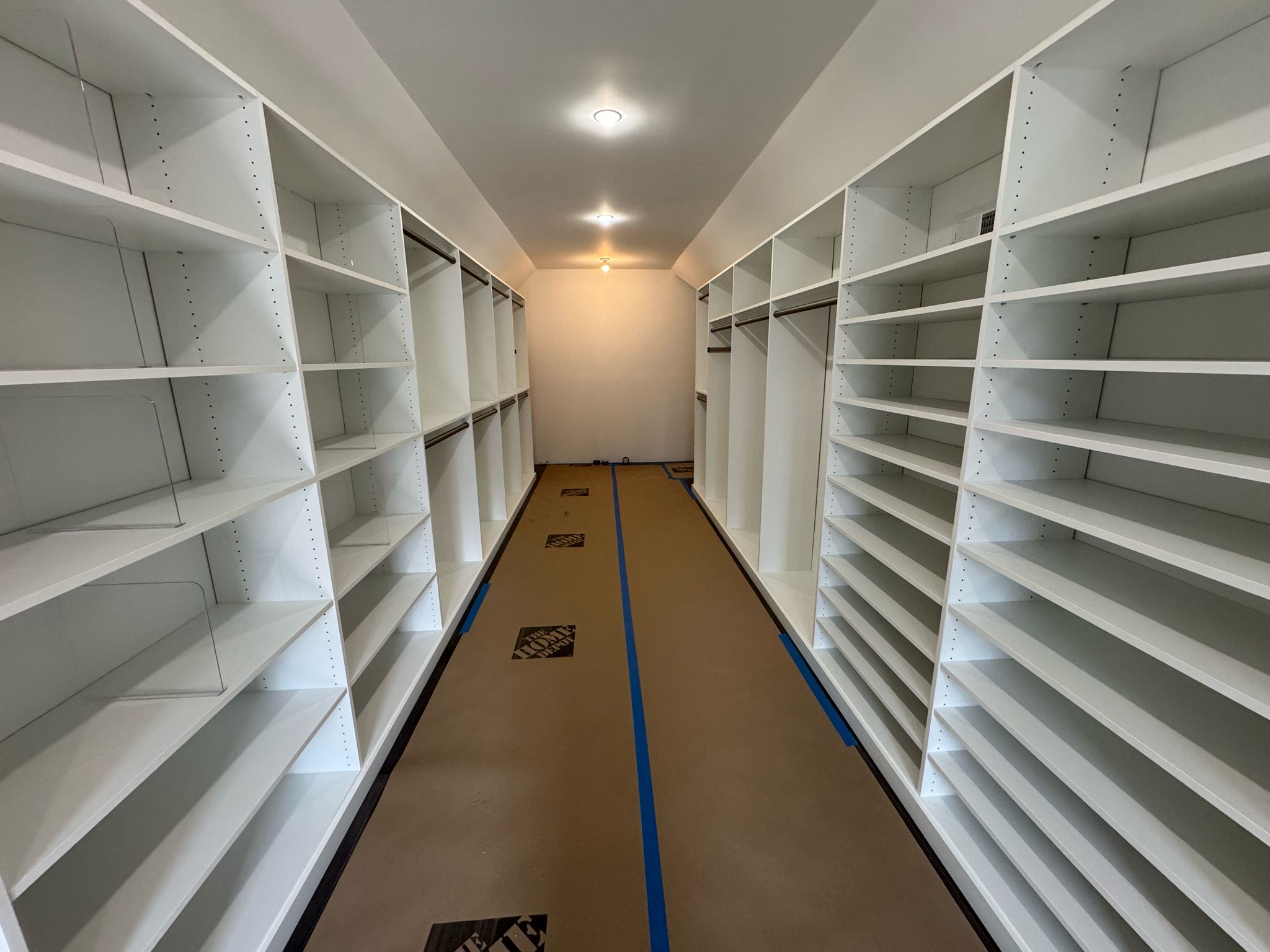 Large walk-in closet during installation showing extensive white shelving systems