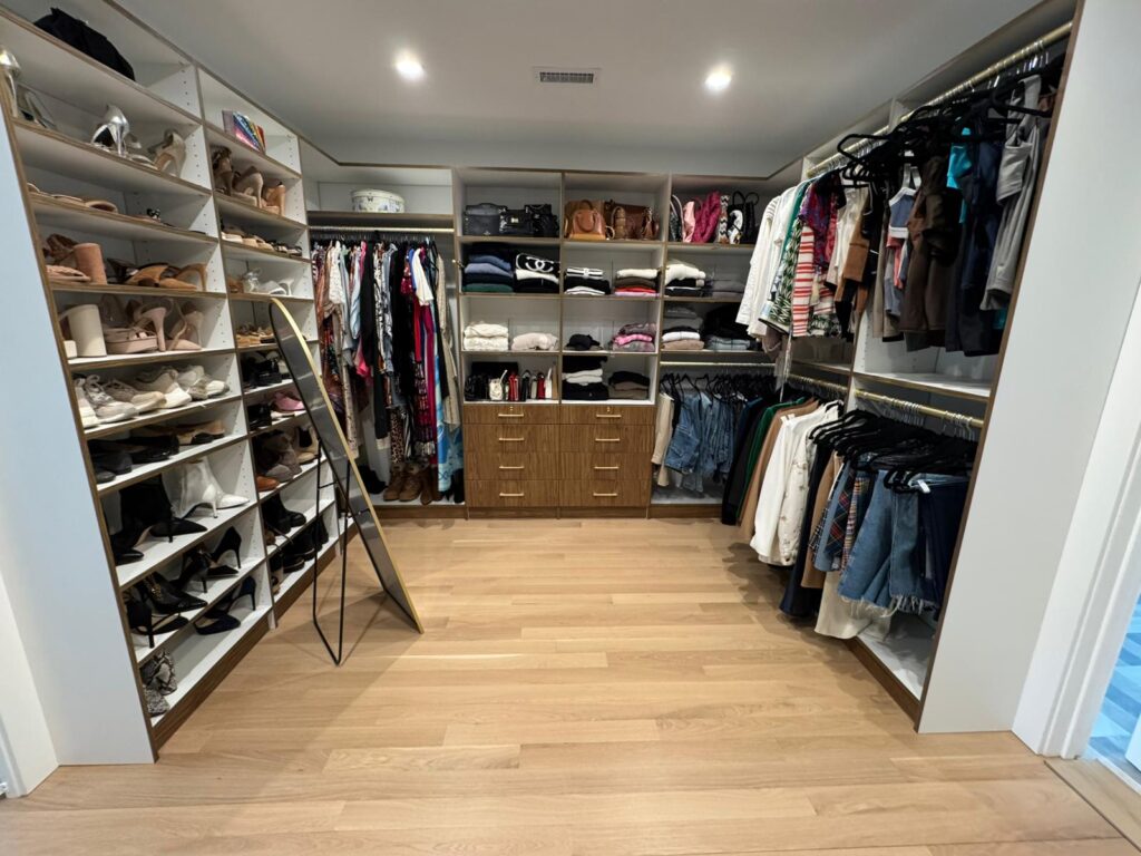Lived-in walk-in closet with extensive shoe collection, hanging clothes, and organized storage