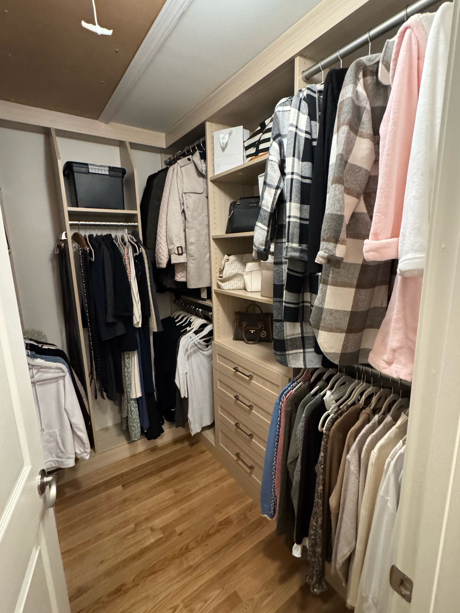 Lived-in walk-in closet with wood-tone organizational systems and daily wardrobe storage