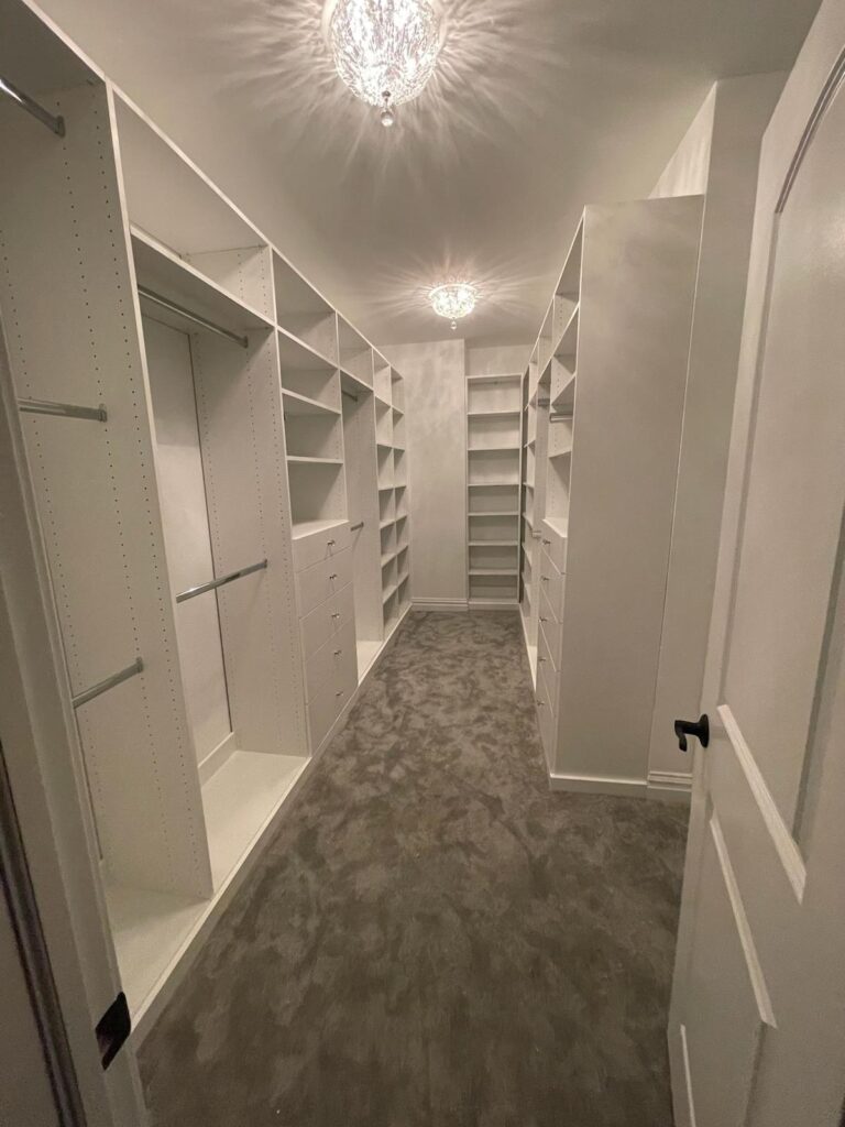 High-end walk-in closet with crystal chandeliers and extensive white storage systems