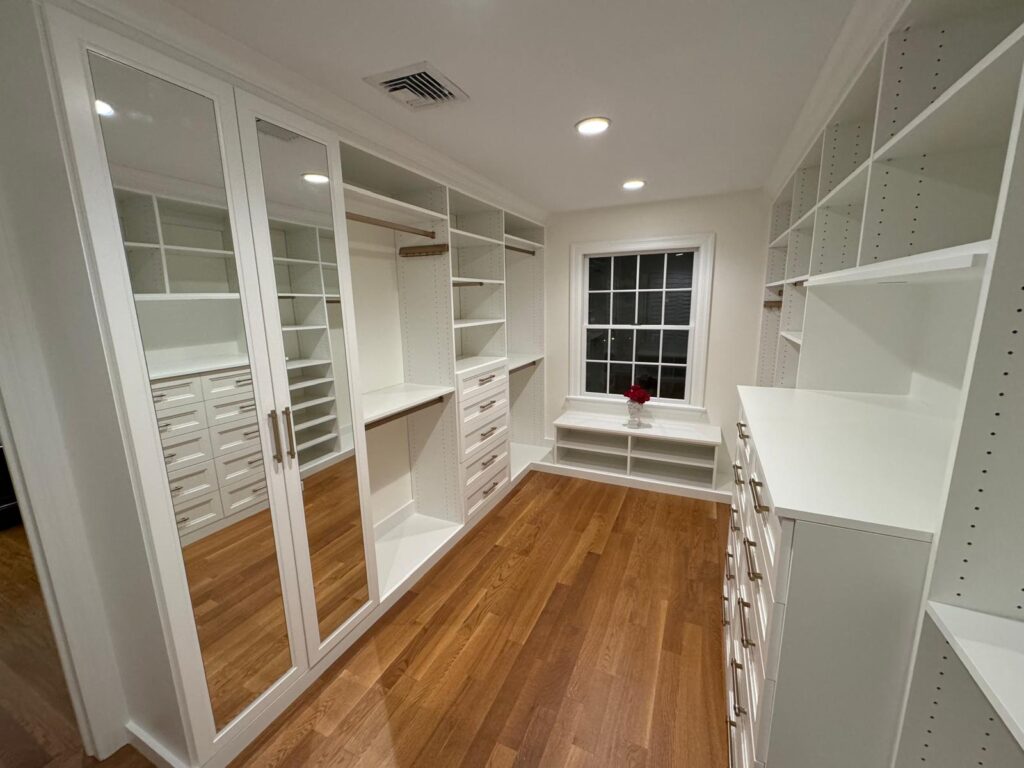 Luxury walk-in closet with glass doors, window, and sophisticated storage systems