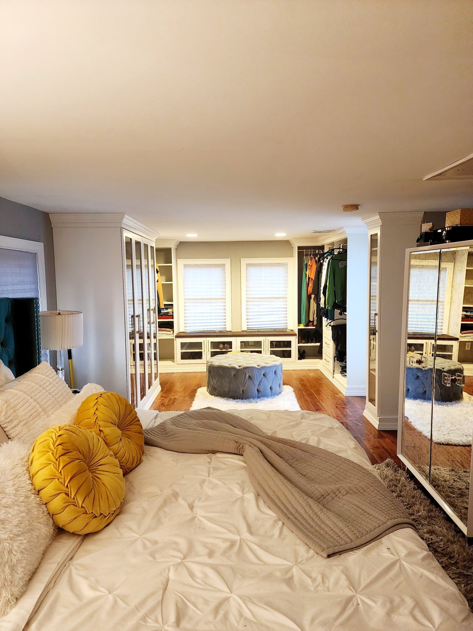 Luxury walk-in closet integrated into master bedroom with custom white cabinetry and shoe storage
