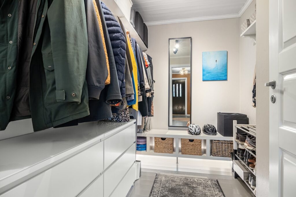 White mudroom storage bench with coat hooks and organized cubbies for entryway organization