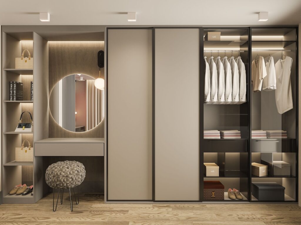 Modern reach-in closet with glass-front wardrobes, vanity area, and neutral color scheme