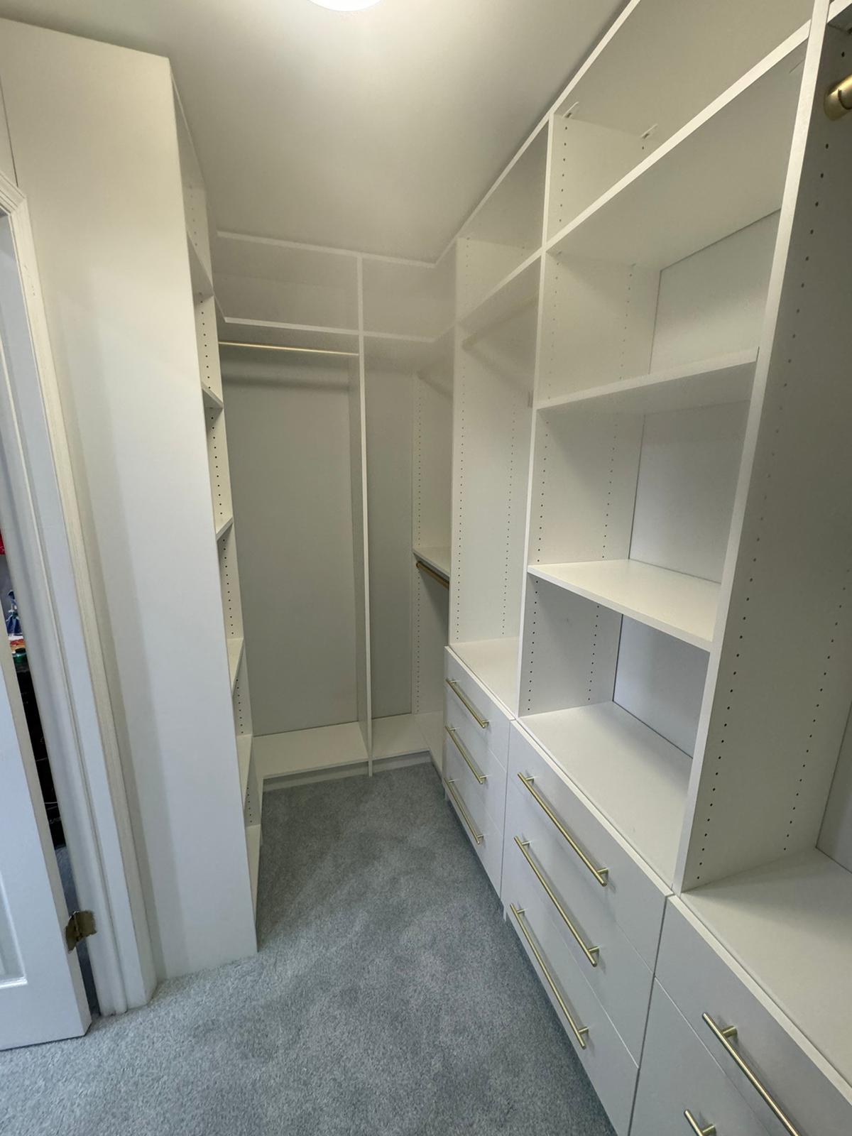 Small empty corner walk-in closet with efficient white storage and corner optimization