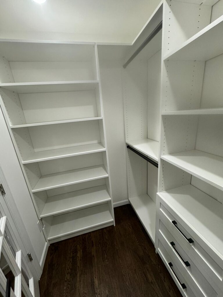Small empty walk-in closet with white organizational systems and efficient space design
