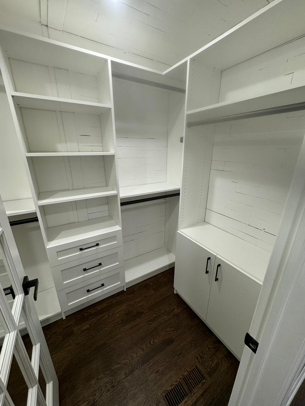 Walk-in closet featuring white organizational system with built-in drawer units and shelving