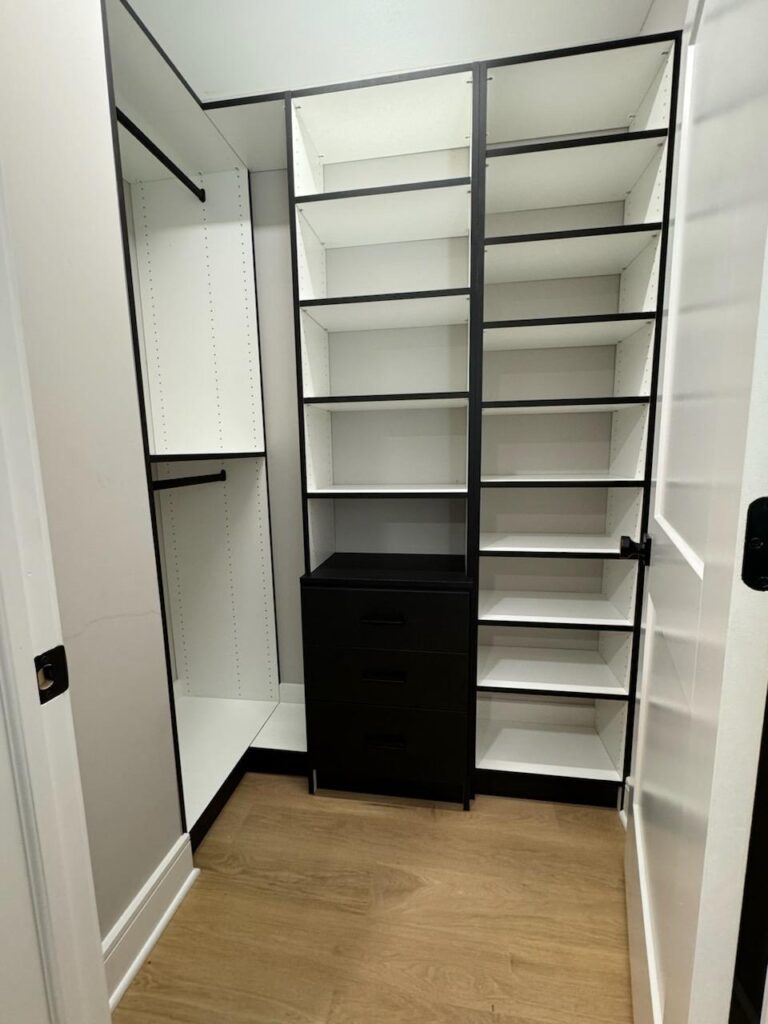 Walk-in closet with black accent drawer unit and white shelving systems