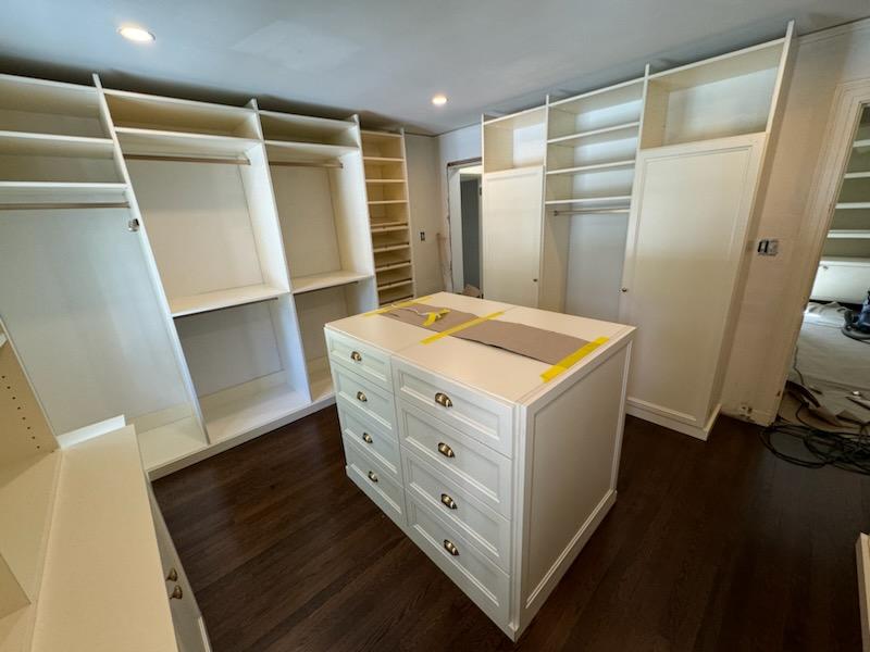 Walk-in closet installation in progress featuring center island and surrounding storage systems
