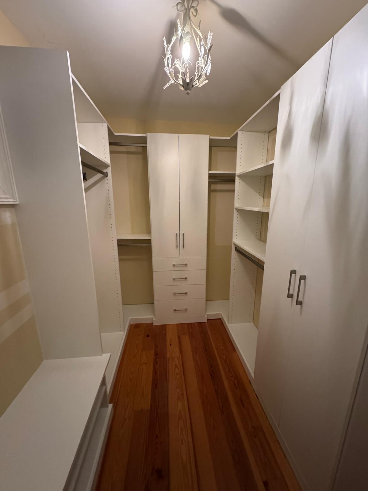 Walk-in closet featuring decorative chandelier and elegant white storage systems