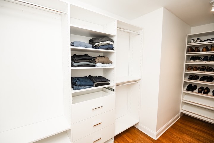 Walk-in closet featuring custom white storage with pull-out drawers and organized shelving systems
