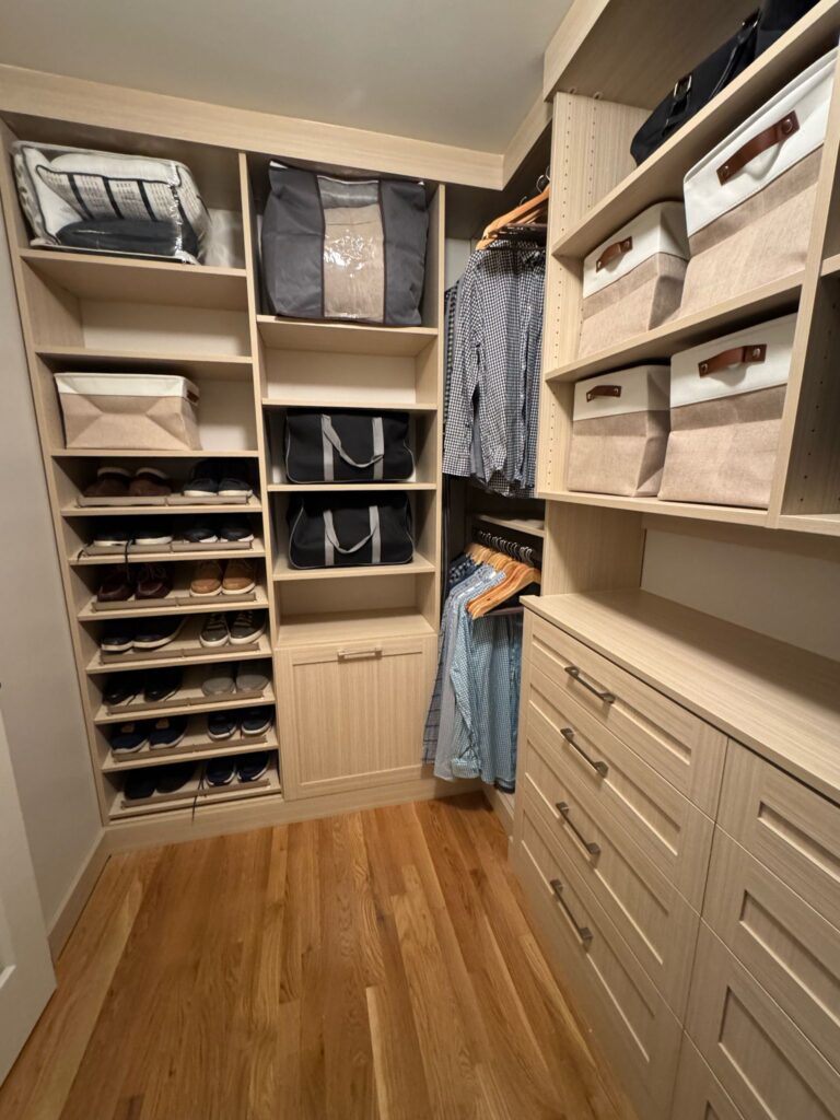 Walk-in closet with completed shoe display featuring wood-tone systems and extensive footwear storage