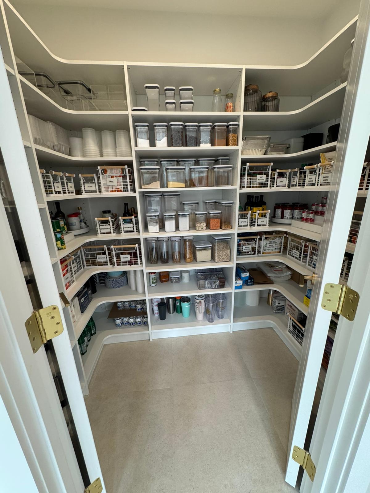 Walk-in pantry with organized food storage containers, labeled systems, and efficient shelving